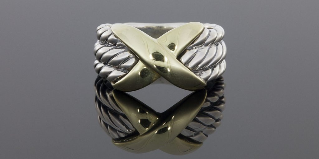 This beautiful ring is from the Crossover Collection and features this signature cable design. It features 3 sterling silver, cable designed rows with a yellow gold "X" in the center. The ring measures 11mm wide at the top, tapering to 5mm at the base. It is currently a finger size 6.25 and is sizable upon request. We bought this for $75.